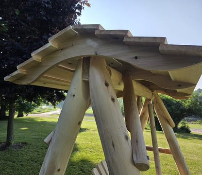 Wooden porch swing with canopy from Cedar Creek Rustic Furniture, featuring a sturdy frame and comfortable seating for outdoor relaxation.